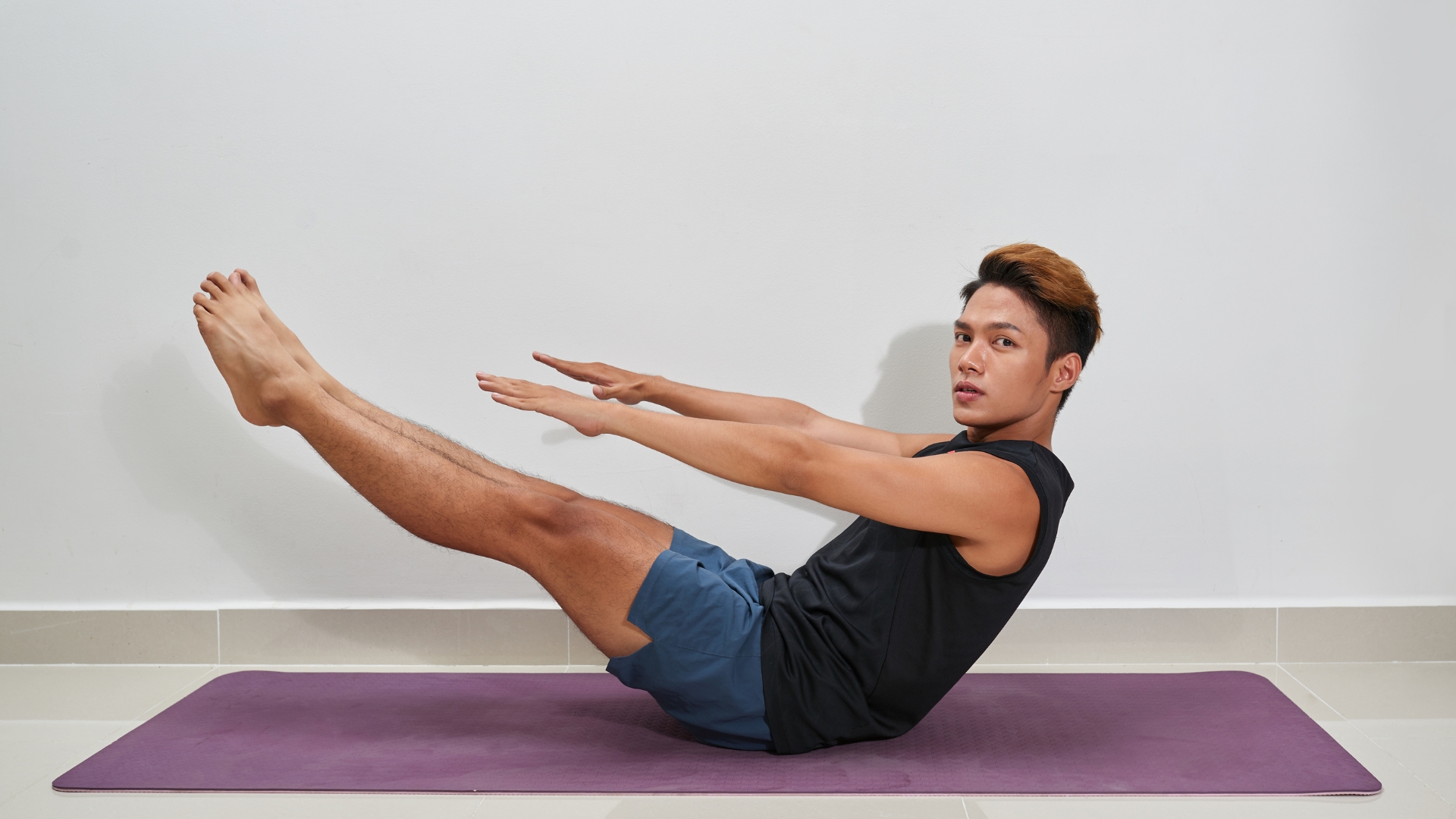 Nhấc hai chân khỏi sàn, từ từ duỗi thẳng về phía trước đồng thời duỗi tay ra trước để giữ cân bằng