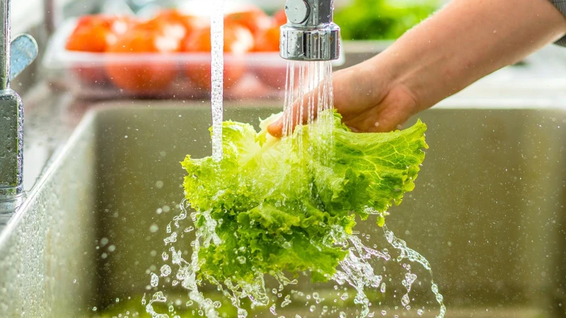 Rửa sạch rau củ dưới vòi nước chảy là bước quan trọng để đảm bảo an toàn