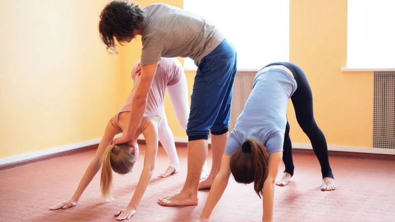 Huấn luyện viên hướng dẫn người mới điều chỉnh tư thế yoga