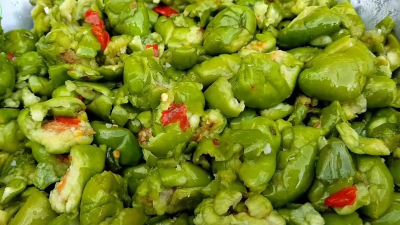 Cà na tươi được chần sơ, đập dập nhẹ rồi trộn muối ớt, tạo vị giòn cay đậm đà